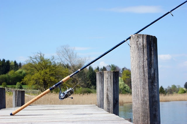 Ett fiskespö som lutar mot räcket på en brygga.
